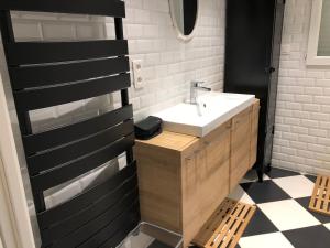 ein Badezimmer mit einem weißen Waschbecken und einem schwarz-weißen Fliesenboden in der Unterkunft 2 Rue de l'Église in Aizecourt-le-Haut