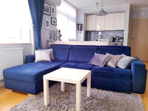 ヤストシェンビャ・グラにあるApartMorze apartamenty Fregataのリビングルーム(白いテーブル付きの青いソファ付)