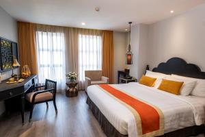um quarto de hotel com uma cama grande, uma secretária e uma cadeira em Sanouva Saigon Hotel em Cidade de Ho Chi Minh