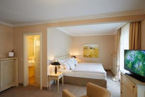a bedroom with a bed and a flat screen tv at Strandhotel Fontana in Timmendorfer Strand