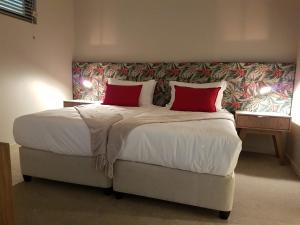 a bedroom with a large bed with two red pillows at 203 zimbali suites in Ballito +15 photos