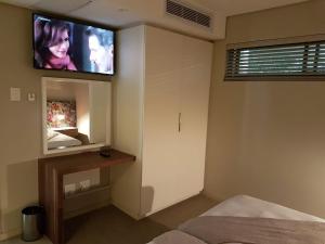 a bedroom with a flat screen tv on the wall at 203 zimbali suites in Ballito