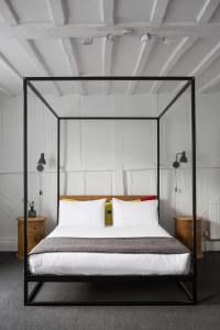 een slaapkamer met een zwart hemelbed met witte kussens bij Whitehouse Rye in Rye