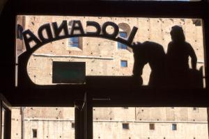 een man op een bord voor een gebouw bij Albergo Locanda Garibaldi in Siena
