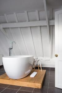 a bathroom with a large white bath tub on a wooden board at Whitehouse Rye in Rye