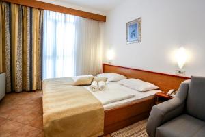 a hotel room with a bed and a chair at Hotel Dražica - Hotel Resort Dražica in Krk