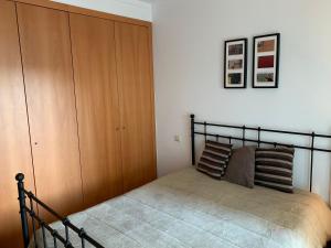 アルブフェイラにあるCasa das Areiasのベッドルーム1室(ベッド1台付)、木製キャビネットが備わります。