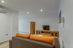 a living room with a couch and a tv at Hotel Apartamentos Loto Conil in Conil de la Frontera