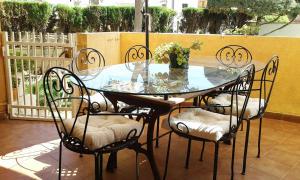 a glass table with four chairs and a vase on it at Apartamento Playa las Marinas in Denia