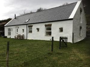 a white house with a fence in front of it at Comraich in Tokavaig