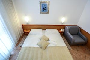 a bedroom with a white bed and a chair at Hotel Dražica - Hotel Resort Dražica in Krk