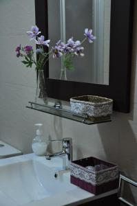 a bathroom sink with a vase of flowers on a mirror at Hostal Rural Letur in Letur