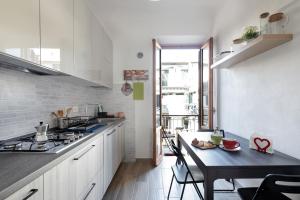 una cucina con armadi bianchi e tavolo nero di Giardino della Fortezza Apartment a Firenze