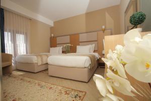 two beds in a hotel room with white flowers at Capital Tirana Hotel Bruçi in Tirana