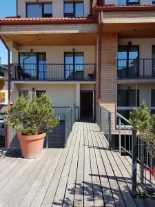 a building with two potted plants on a wooden deck at Maluno Vilos in Palanga