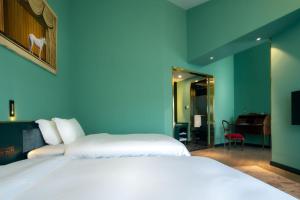 a bedroom with two white beds and a blue wall at Moon and Chalice Boutique Hotel in Kunming