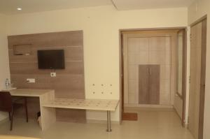 a room with a desk and a door with a television at Hotel kanakabhishegam First Hotel From The Thirukadaiyur Temple in Tirukkadaiyūr