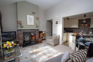 a living room with a fireplace and a kitchen at Tethera at Coal Yeat in Spark Bridge