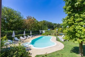 a swimming pool in a garden with lounge chairs and umbrellas at Villa La Quiete in Mogliano