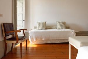 a white bedroom with a bed and a chair at Pensao Favorita in Porto