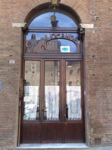 een grote houten deur op een bakstenen gebouw bij Albergo Locanda Garibaldi in Siena