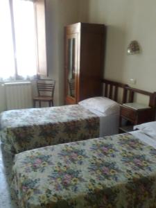 una camera d'albergo con 2 letti e una scrivania di Albergo Locanda Garibaldi a Siena