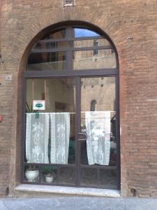 een raam met witte gordijnen in een bakstenen gebouw bij Albergo Locanda Garibaldi in Siena