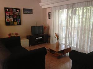 Palermo Soho Hostel في بوينس آيرس: غرفة معيشة مع أريكة وتلفزيون