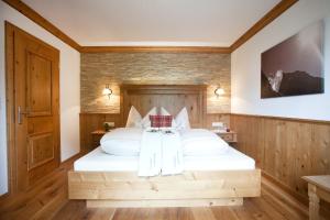 a bedroom with a large white bed with wooden walls at Brixnerhof im Zillertal in Schlitters