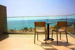 a table and two chairs in a room with a view of the ocean at Amphora Hotel & Suites in Paphos