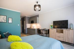 a bedroom with a bed with a television and a kitchen at Apartamenty Świnoujście - Wyspiańskiego 34e in Świnoujście
