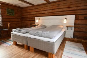 a room with two beds in a wooden cabin at Kolarbogård in Fors
