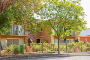 a building with a fence and a tree in front of it at Angaston Mews Apartments in Angaston