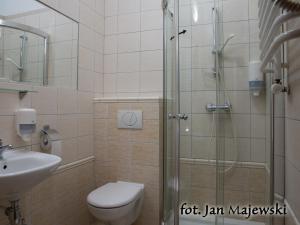 a bathroom with a shower and a toilet and a sink at Majewski Hotel & SPA in Malbork