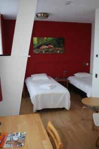 two beds in a room with a red wall at Hotel Saint Vincent in Poeldijk