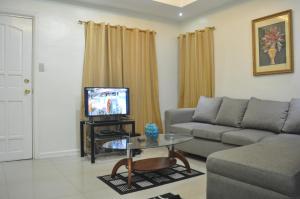 a living room with a couch and a tv at Fe and Jun Condo Unit Rental in Baguio