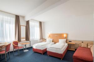 a hotel room with two beds and a table and chairs at Sure Hotel by Best Western Ratingen in Ratingen