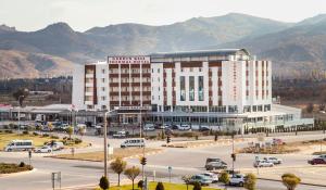 a large white building with a parking lot with cars at GARDEN KALE THERMAL HOTEL in Afyon