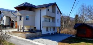 a large white house with a red garage at Apartmani Bilić in Korenica