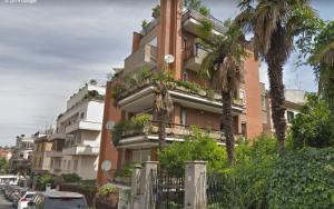 een hoog gebouw met palmbomen ervoor bij L'Attico di San Saba in Rome
