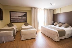a hotel room with two beds and a large window at Olavo Bilac Hotel in Taubaté