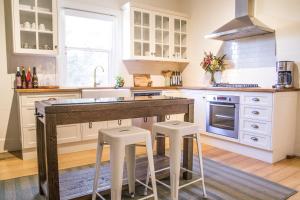a kitchen with white cabinets and a wooden island with stools at Mataro Cottage in Tanunda