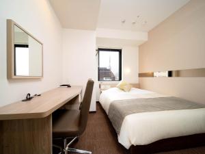 a hotel room with a desk and a bed and a mirror at Super Hotel Tokyo Hamamatsucho in Tokyo