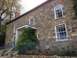 an old stone house with a fence at The Farmhouse at Bodnant Welsh Food in Conwy