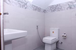 a white bathroom with a toilet and a sink at Turtle Reef Guest in Mirissa