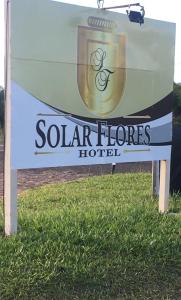 a sign for a solar floors hotel on the grass at Hotel Solar Flores in Alegrete