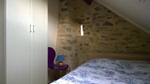 een slaapkamer met een bed en een paarse stoel bij Gite Bleu in MÃ©nil-Vin
