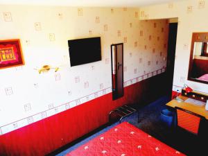 Habitación con TV y pared roja y blanca. en Le relais du Haut Limousin, en Eymoutiers