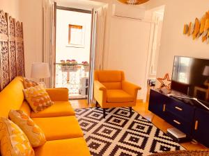a living room with a yellow couch and a television at Apartments Alfacinha Ajuda in Lisbon