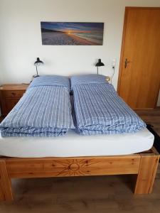 Una cama con dos almohadas azules encima. en Ferienwohnung Haffblick, en Westerholz